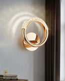 Gold and wood rotatable wall lamp with a luxurious metallic design, featuring ornate details resembling musical instruments and jewelry, set against a door with a circular door handle.