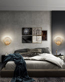 Luxurious metallic wall lamp with a rotatable angle, featuring a black finish and set against an interior backdrop with wooden and textile elements.