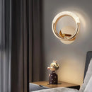 Luxurious metallic wall lamp with adjustable angle, elegantly positioned in a well-designed interior featuring a mirror, wooden table, curtains, art decorations, and a trophy near a window.