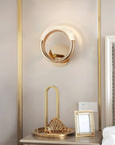 Luxurious metallic rotatable wall lamp with a golden finish, displayed in an elegant interior featuring wooden elements and modern furniture.
