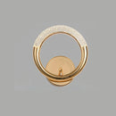 Luxurious metallic wall lamp with a rotatable angle feature, designed to resemble an elegant piece of jewelry with a circular rim and wood accents.