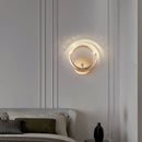 Luxurious metallic wall lamp with a rotatable angle mounted on a white wall above a grey pillow, featuring wooden interior design elements.