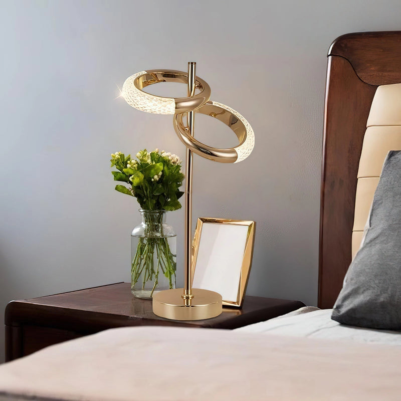 A wall lamp with a rotatable design illuminating a cozy interior space with furniture and a table, complemented by a plant and vase, all against a wooden backdrop.