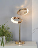 A Nordic style wall lamp with a rotatable design displayed on a wooden table, surrounded by plants and twigs.