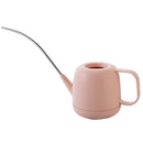 Modern and functional April Showers garden watering can in magenta plastic, styled on a table among various household items.