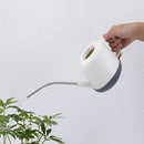 Modern and functional April Showers Garden Watering Can surrounded by flowers and plants under a clear sky.