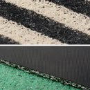 Geometric entrance doormat inspired by Back to the Future, featuring rectangular design elements, placed on a textured surface that resembles asphalt and grass.