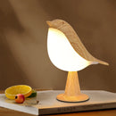 Dimmable LED bird-shaped lamp on a wooden nightstand, surrounded by citrus fruits and elegant tableware.