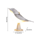 Dimmable LED bird-shaped lamp on a wooden nightstand, featuring artistic metal accents and a cordless design.