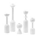 Set of five white wooden candle holders in various sizes arranged for a still life home decor display.