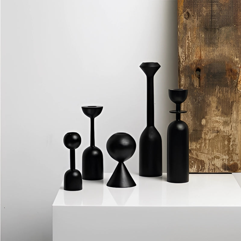 Black wooden candle holder set displayed on a table, featuring cylindrical shapes and crafted from wood and glass, ideal for home decor.