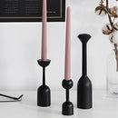 Set of black wooden candle holders on a shelf, used for home decor.