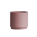Stack of bright porcelain flowerpot planters in cylinder shapes, featuring magenta and peach colors with decorative patterns.