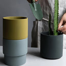 Stack of bright porcelain flowerpot planters with various houseplants, featuring green foliage.
