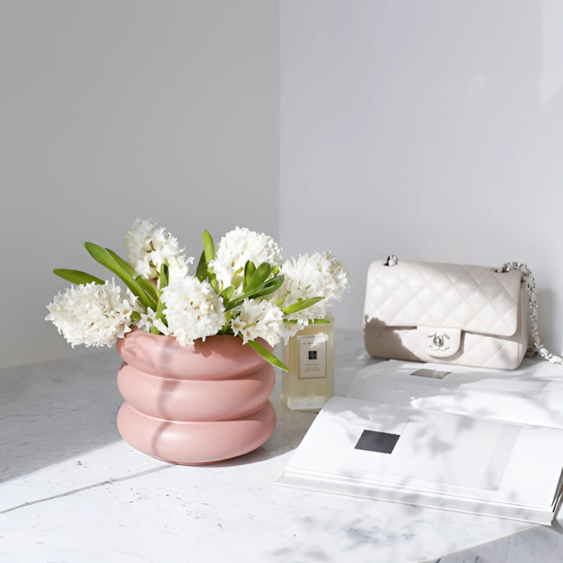 Round ceramic bubble glass planter vase on a table, filled with flowers and plants, near a couch.