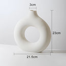 Large white ceramic vase in a donut shape, featuring an oval opening ideal for modern home decor.