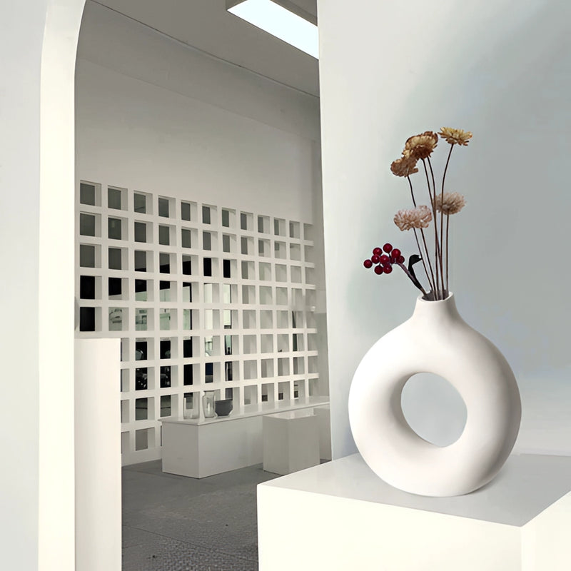 Modern ceramic donut-shaped vase displayed in an interior setting, showcasing artistic and architectural elements with a focus on material properties and design aesthetics.