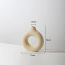 Beige ceramic donut-shaped vase for modern home decor, featuring a unique circular design with artistic wood and metal elements, styled on a ceiling fixture background.