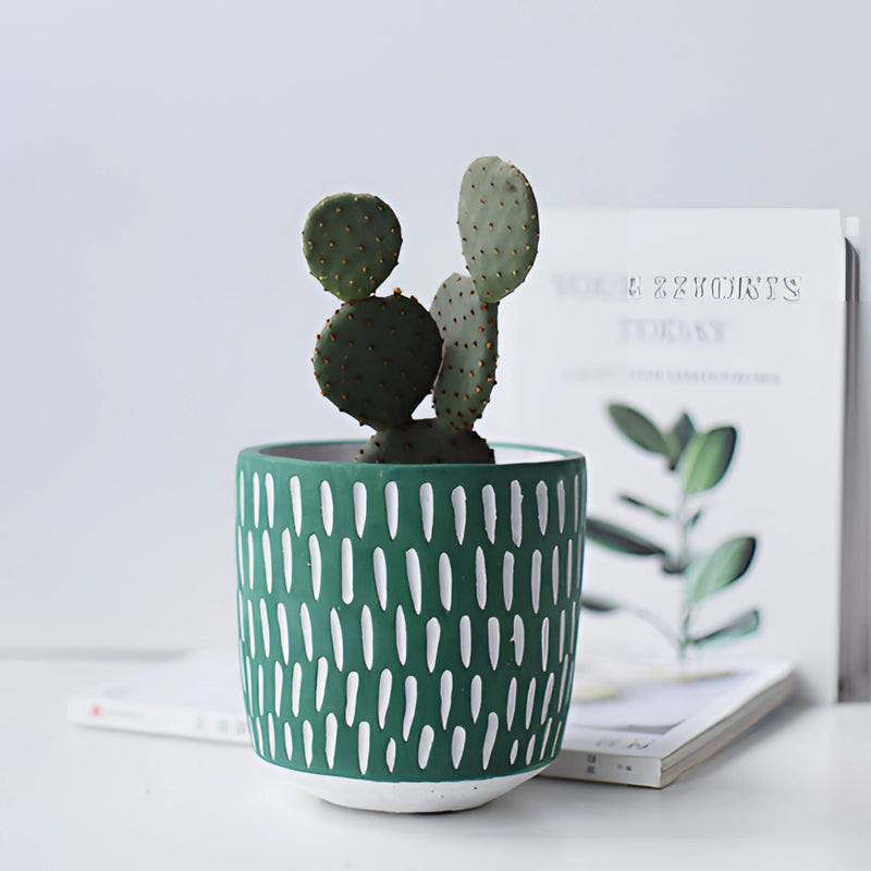 Colorful ceramic hand-painted planters with textured designs, featuring aqua shades and artistic patterns, displayed on a table surrounded by other dishware and tableware elements.