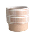 Ceramic plant pots with island holiday designs, featuring cylindrical and circular shapes, displayed on a wooden surface with metallic and leather fashion accessories.