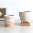 Ceramic Island Holiday Plant Pots displayed on a wooden table, featuring grey wood stain and other tableware elements around.