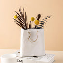 Ceramic vase designed to resemble a shopping basket, featuring artistic twig and tree elements.