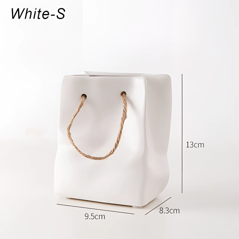 Small white ceramic vase designed to resemble a shopping basket, featuring intricate details that mimic metal chain jewelry.