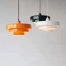 Modern metal pendant lamp featuring linked circle designs, suspended from a ceiling, with a rectangular wood backdrop enhancing tints and shades.