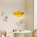 Modern metal pendant lamp featuring interlinked circles in yellow, with switchable color temperatures, displayed in a stylish interior with white furniture and wood accents.