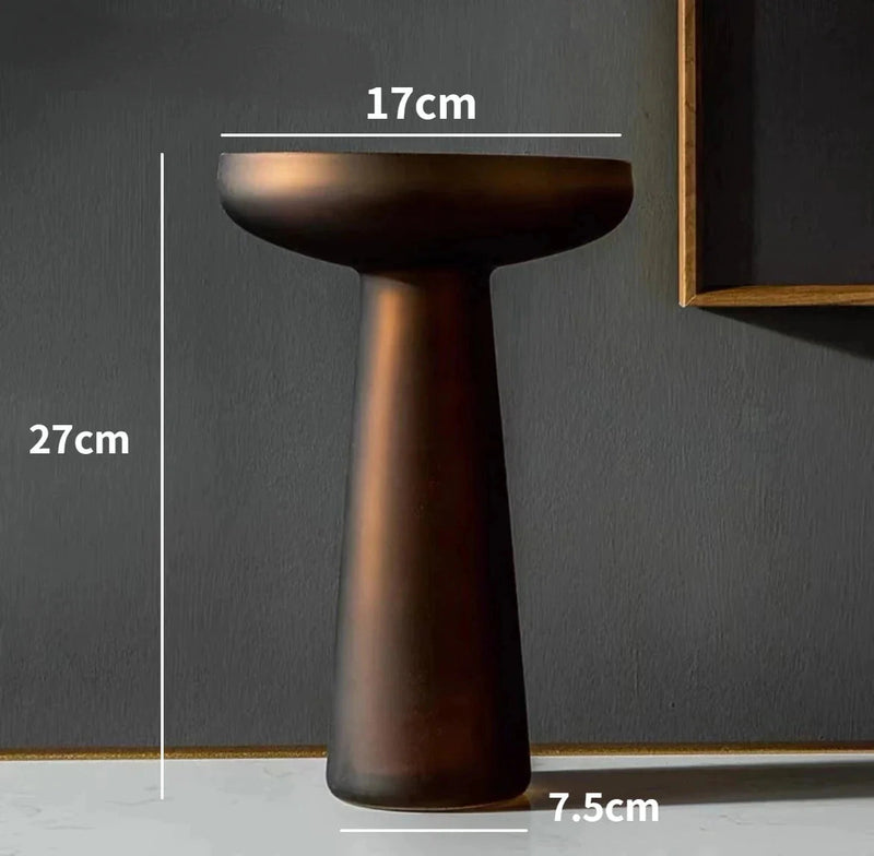Coffee-colored frosted glass vase displayed on a wooden pedestal table, highlighting its unique texture and elegant shape.