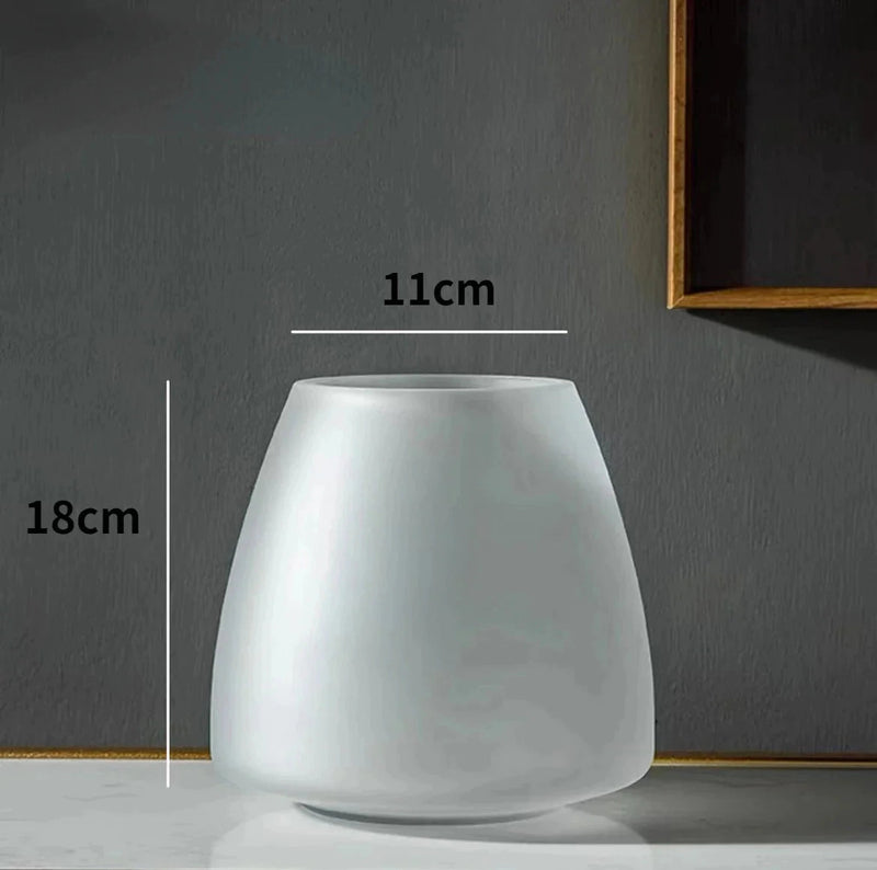 Coffee-colored frosted glass vase on a table, variant Transparent B, featuring a lamp and artistic elements in the background.