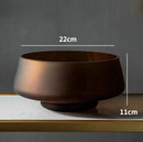 Coffee-colored frosted glass vase on a wooden table, featuring a rectangular shape with soft, translucent texture.