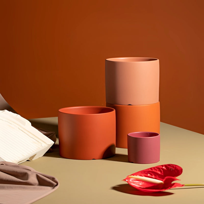 Colorful ceramic planter and saucer set displayed on a wooden table in a room, complemented by office supplies and decorative tissue paper.
