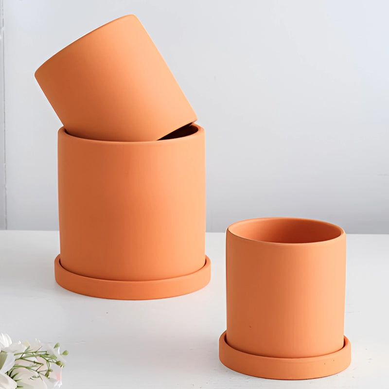 Colorful ceramic planter and saucer set displayed on a table, featuring vibrant orange tones and intricate designs, commonly used for home decor.