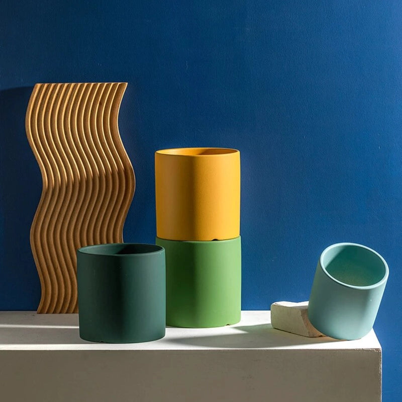 Colorful ceramic planter and saucer set featuring cylindrical vase shapes, displayed on a wooden surface, with artistic design elements.