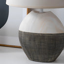 Beige contemporary lampshade table lamp on a wooden side table, complemented by wicker chairs and cozy living room decor.
