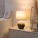 Contemporary lampshade table lamp on a wooden table, featuring a unique design suitable for living room and bedroom settings, enhancing the interior with subtle lighting and artistic elements.