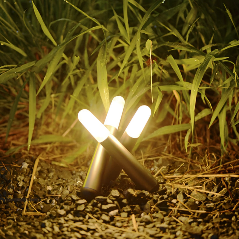Cordless Kinetic Rotation LED Table Lamp placed on a wooden surface surrounded by plants and grass in a natural outdoor setting.