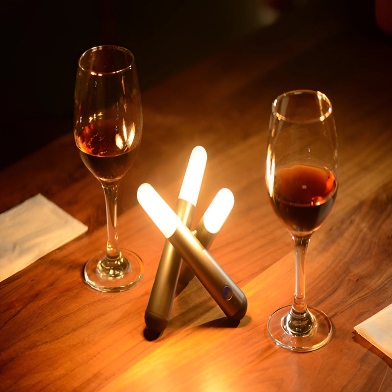 A cordless kinetic rotation LED table lamp illuminates a table set with wine glasses and an assortment of drinks.