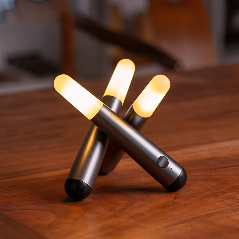 Frosted cordless kinetic rotation LED table lamp on a varnished hardwood desk surrounded by office supplies like pens and stationery.
