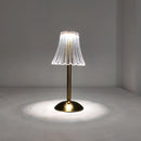 Cordless table lamp featuring a beautiful design with a wooden base and glass accents, surrounded by plants and art elements in a well-lit setting.