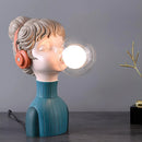 Artistic resin desk lamp in a minimalist design, featuring vibrant orange and green colors, displayed in a fun, still life setting with a backdrop that includes wooden elements and electric blue hues.