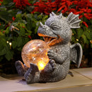 Dragon-shaped LED table lamp designed as a metallic and wooden sculpture resembling a stylized dragon, surrounded by artistic elements and plants.