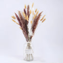 Dried Pampas Grass Flowers Set displayed on a table, featuring 30 pieces including feathery twigs and flowering plants, complemented by artful tableware and a flowerpot, arranged in an indoor setting.
