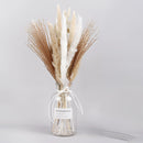 Dried Pampas Grass Flowers 30-piece set displayed artistically on a table, featuring natural twigs and feather-like textures, complemented by subtle tableware and chair in the background, enhancing a home interior.