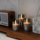 Three-piece flameless glass candle set featuring LED pillar candles displayed on a wooden surface, each with a realistic flame effect, suitable for events or home decor.