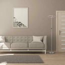 Modern LED floor lamp with touch dimmer control, featuring a sleek metal uplighter design, set in a room with grey flooring, a couch, and wooden elements, enhancing the interior design.