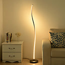 Floor lamp with remote control featuring three light temperature settings, placed next to a wooden dresser in a well-designed interior setting.
