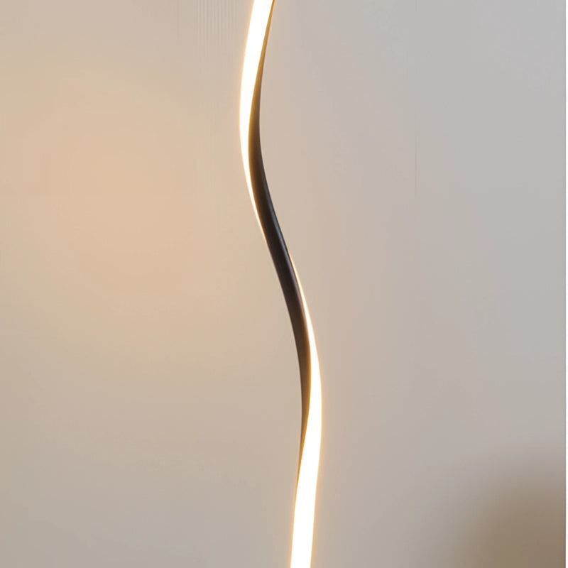 Modern floor lamp featuring a metal base and wooden accents, with a plant and artistic sculpture nearby, designed to offer three different light temperatures controlled by a remote.