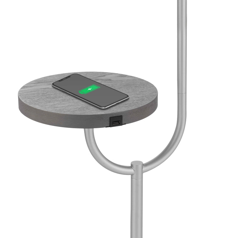 Modern floor lamp featuring a wireless charging station and a built-in table top shelf, surrounded by various everyday items including a watch and communication devices.